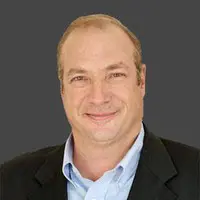 A man in a suit and tie smiling for the camera.