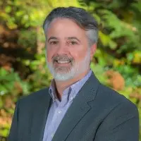 A man with grey hair and beard wearing a suit.